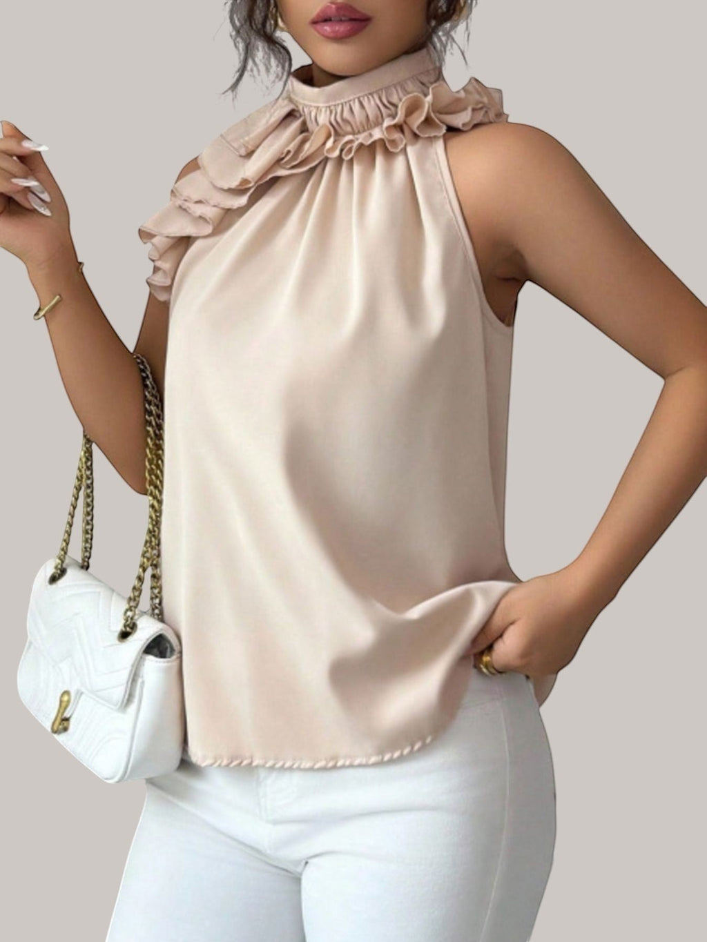 MICHEL beige sleeveless high neck top with ruffled collar detail worn by a model with a white chain strap handbag