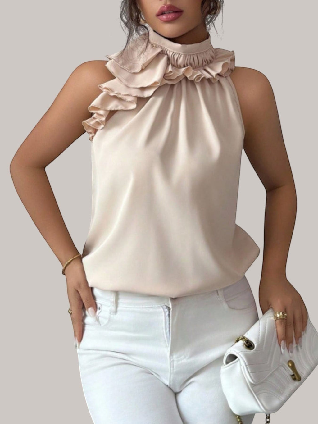 MICHEL beige sleeveless top with a high ruffled neckline and button detail, worn by a model with white trousers.