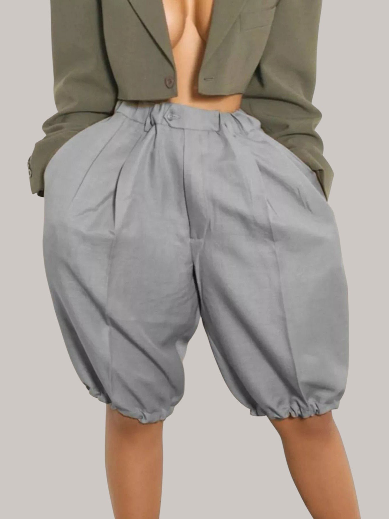 MICHEL high-waisted grey pleated shorts with a drawstring waist and relaxed fit worn with a cropped olive blazer.