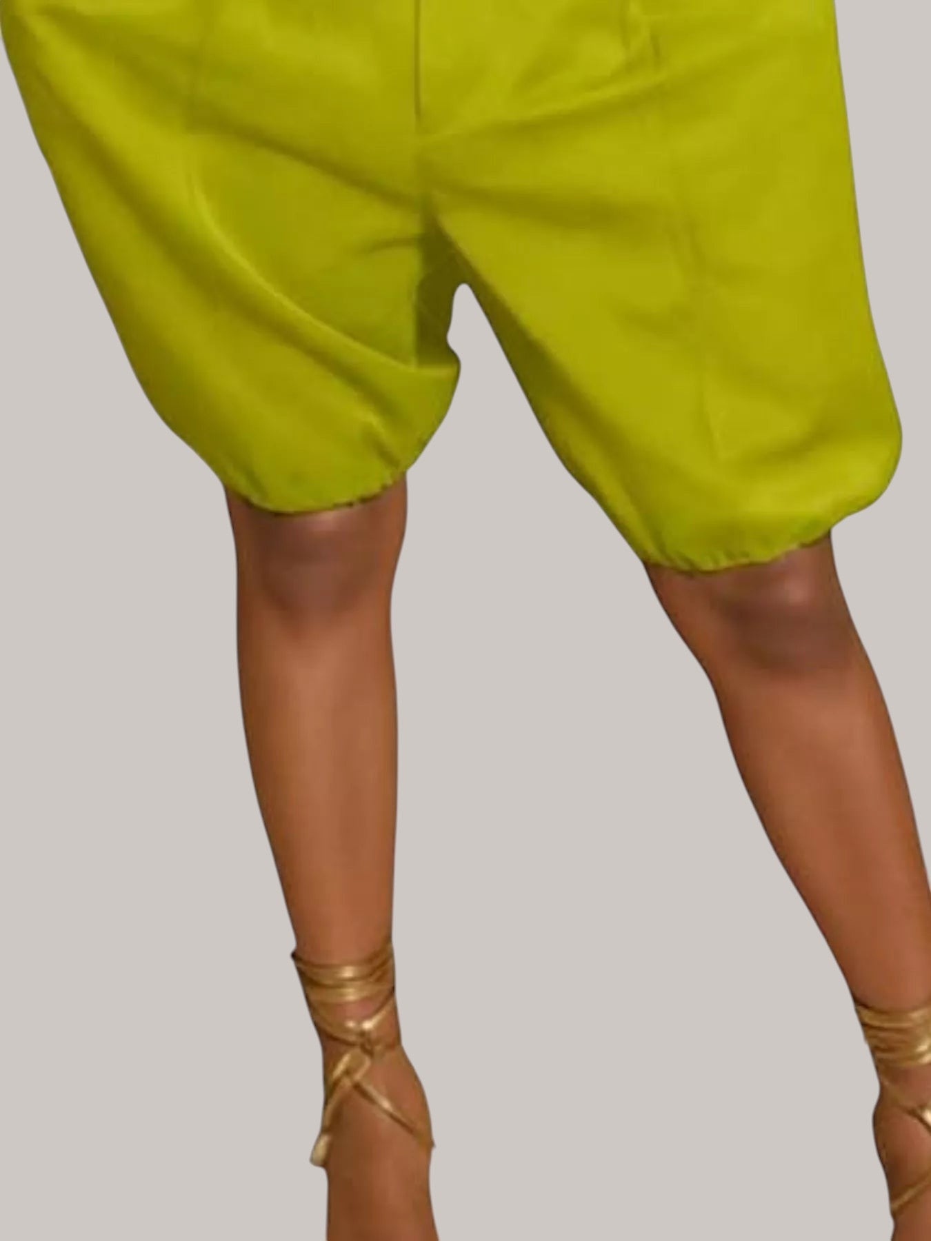 MICHEL lime green high waist pleated shorts with a relaxed fit and drawstring detail worn with gold lace-up sandals